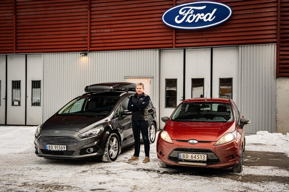 En mann som står utenfor et Ford-verksted mellom en grå Ford S-MAX og en rød Ford Fiesta 