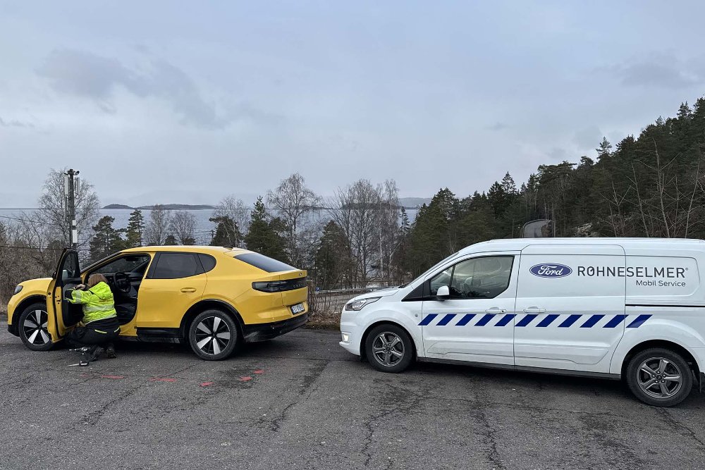 Ford Mobilservice-tekniker utfører et serviceoppdrag på en gul helelektrisk Ford Capri ved siden av en mobilservice-bil.
