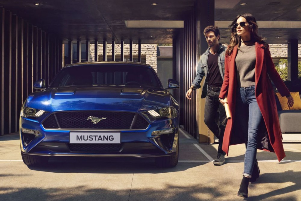 Blå Ford Mustang parkert foran huset