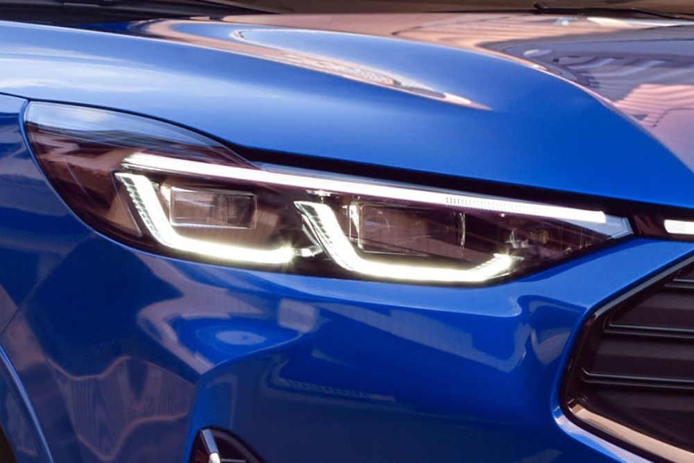 Et nærbilde av frontlyktene på en blå Ford Mustang Mach-E.