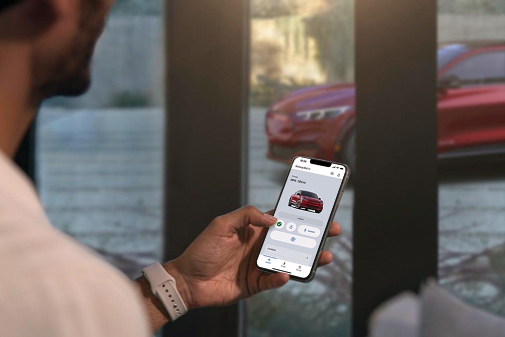 En mann som kontrollerer innstillingene til sin helt nye Ford Mustang Mach-E ved hjelp av de eksterne bilkontrollfunksjonene i FordPass-appen