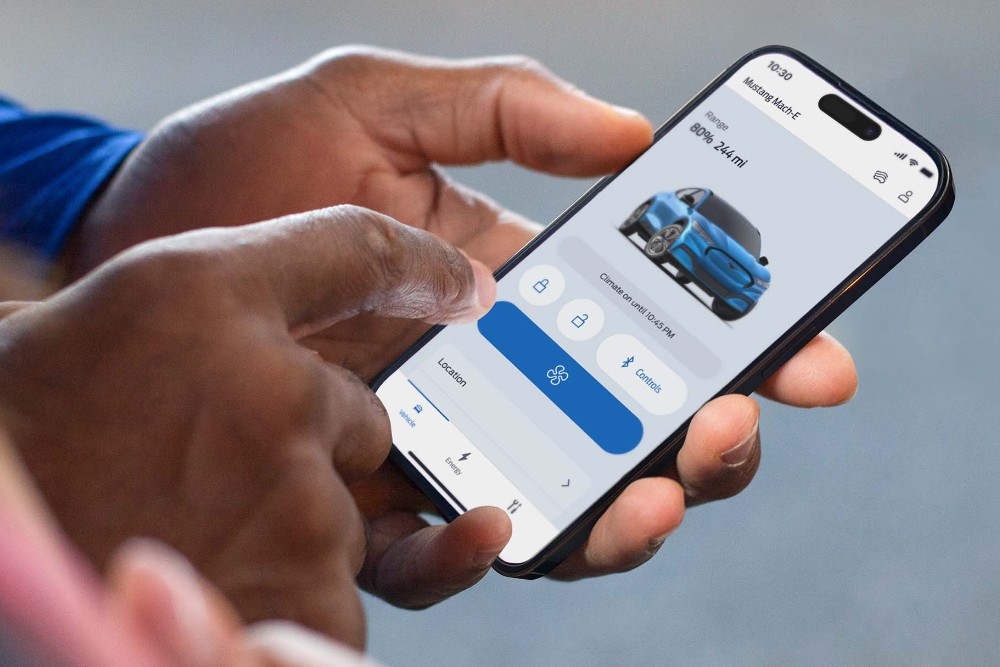 Mann som holder en telefon, bruker fjernlåsing på FordPass-appen