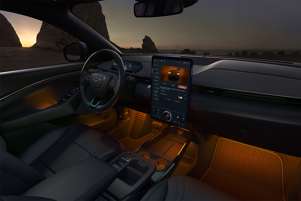 The interior of the Ford Mustang Mach-E at night, showing the 15.5" SYNC 4 touchscreen and ambient LED lighting set to orange