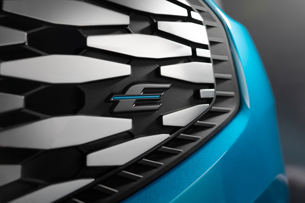 Nærbilde av grillen til Ford E-Tourneo Custom, med den blå «E»-logoen som er eksklusiv for Ford-elkjøretøy.