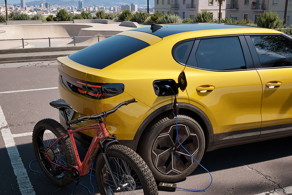 Gul parkert Ford Capri® som lader med en rød elsykkel i urbane byomgivelser