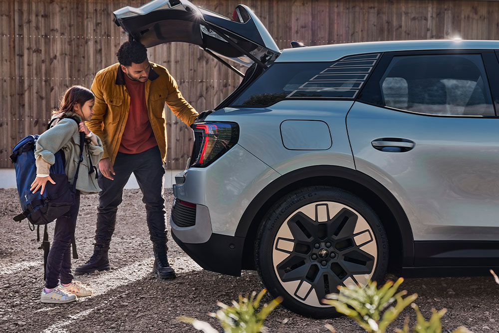 En far og datter som laster inn bagasjerommet på en blå Ford Explorer®.