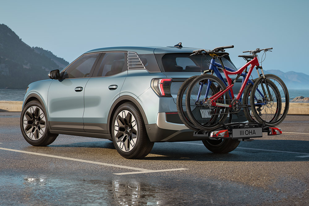 Blå Ford Explorer kjører på støvete vei, med tverrstenger, sykkelstativ og to sykler på taket.