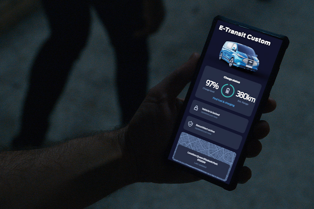 Smarttelefon som viser en E-Transit Custom i Ford-appen, som viser bilens ladestatus og plassering.