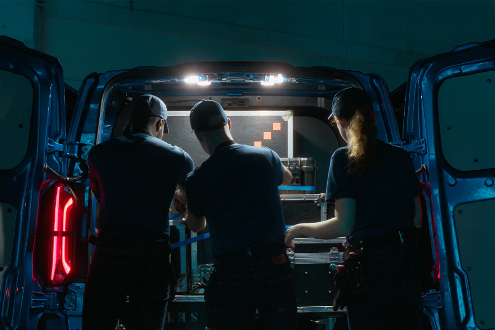 Tre personer som jobber bak i en Ford E-Transit Custom-varebil.