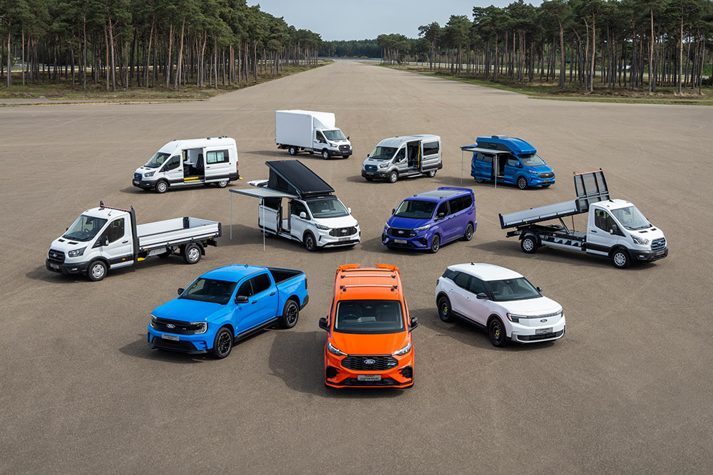 Samling av Ford Transit-varebiler og biler parkert på en flystripe.