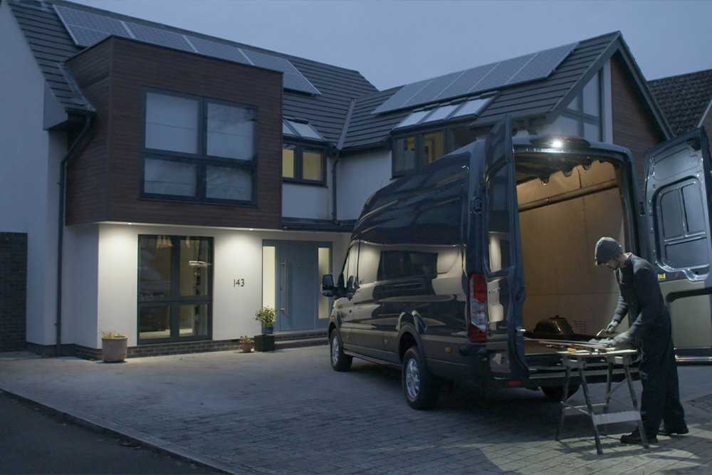 En snekker arbeider bak en Ford Transit varebil med åpne bakdører om natten, opplyst av LED-downlighten.