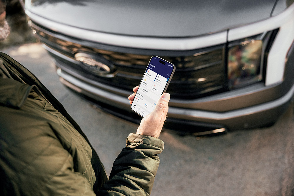 En mann som sjekker smarttelefonen sin foran en Ford Ranger.
