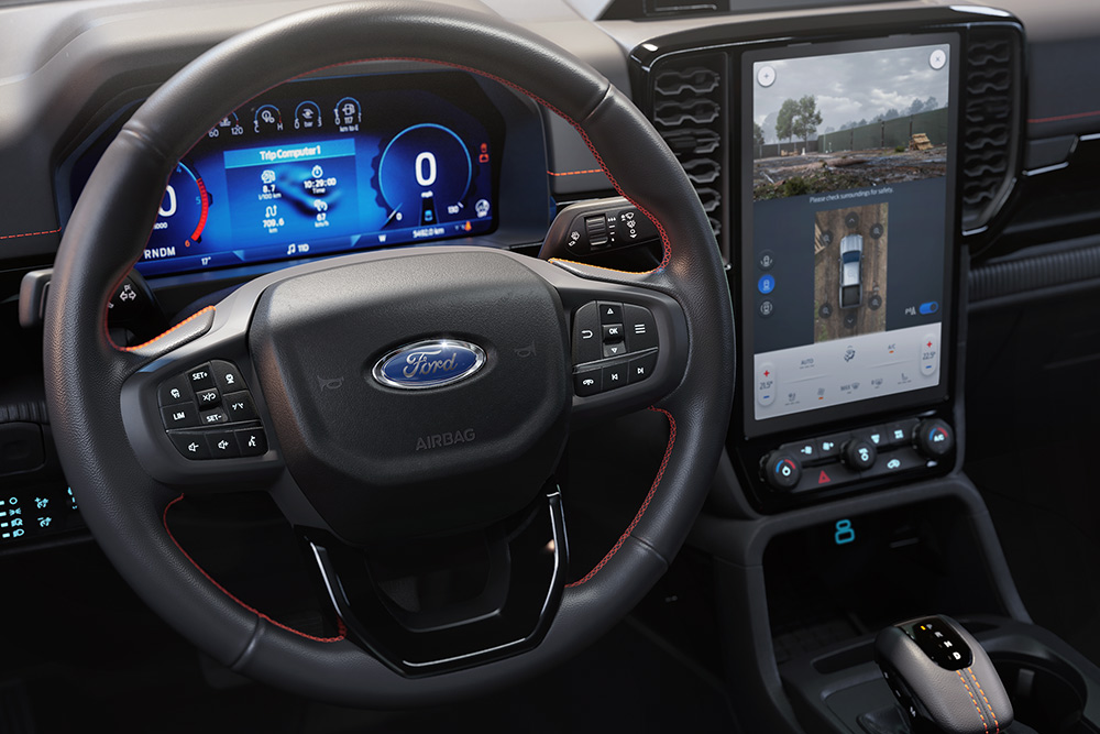 Interiørvisning av Ford Ranger Wildtrak sitt ratt og midtkonsollens 12-tommers SYNC™ 4-touchskjerm.