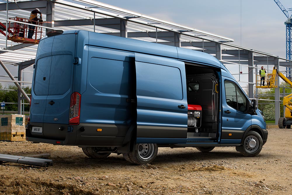 Blå Ford Pro Transit varebil parkert på en byggeplass.