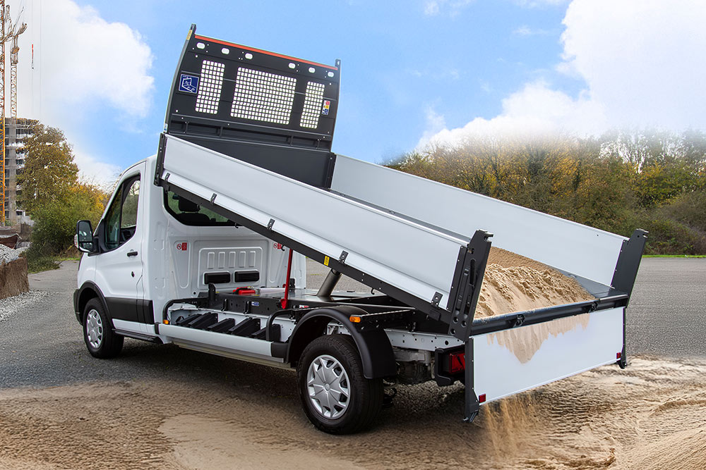 Hvit Ford Pro Chassis Cab med hevet flatbed parkert på en byggeplass.