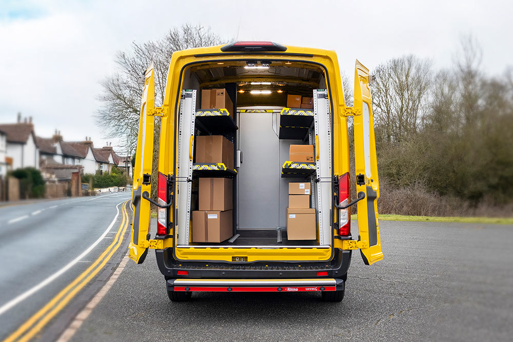 Bakfra-visning av en gul Ford Transit varebil med åpne dører, som avslører et organisert interiør med hyller og esker.