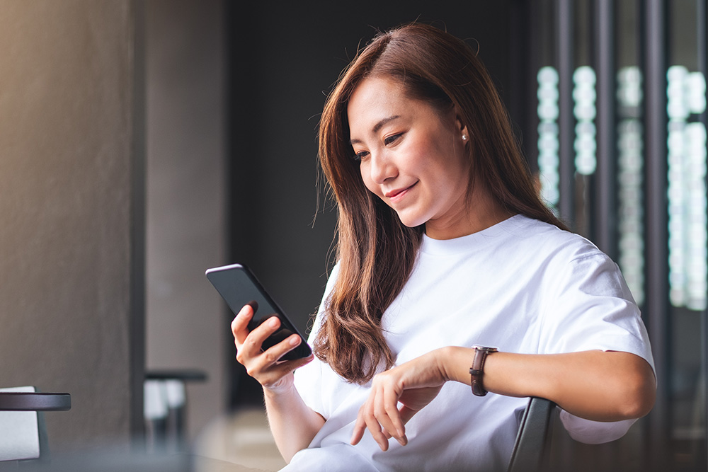  Kvinne sjekker sanntidsvarsler fra FordPass-appen på mobilenheten sin.